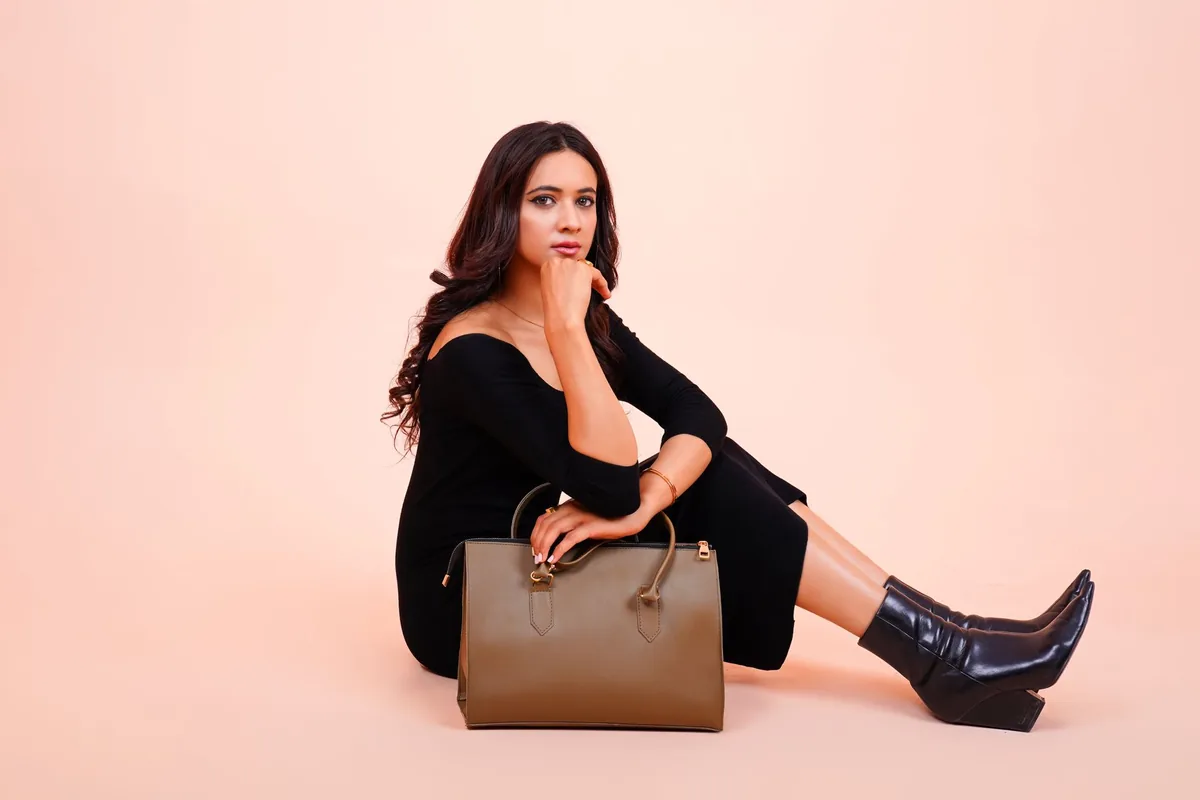 Stylish woman in black attire with a leather handbag, posing elegantly.