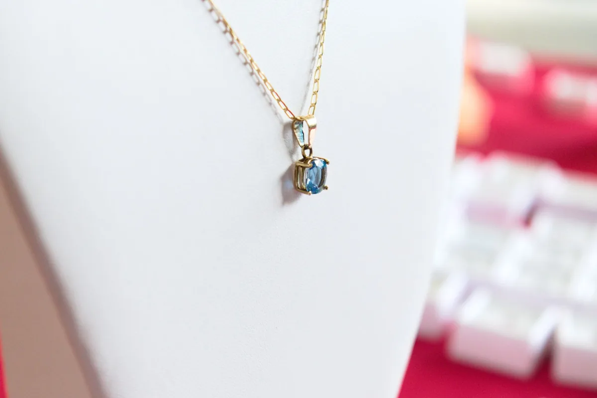 Delicate gold necklace featuring a stunning blue gemstone pendant on display.